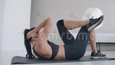 白人黑发女人躺在地毯上做腹肌锻炼。 每天在家锻炼身体，保持健康